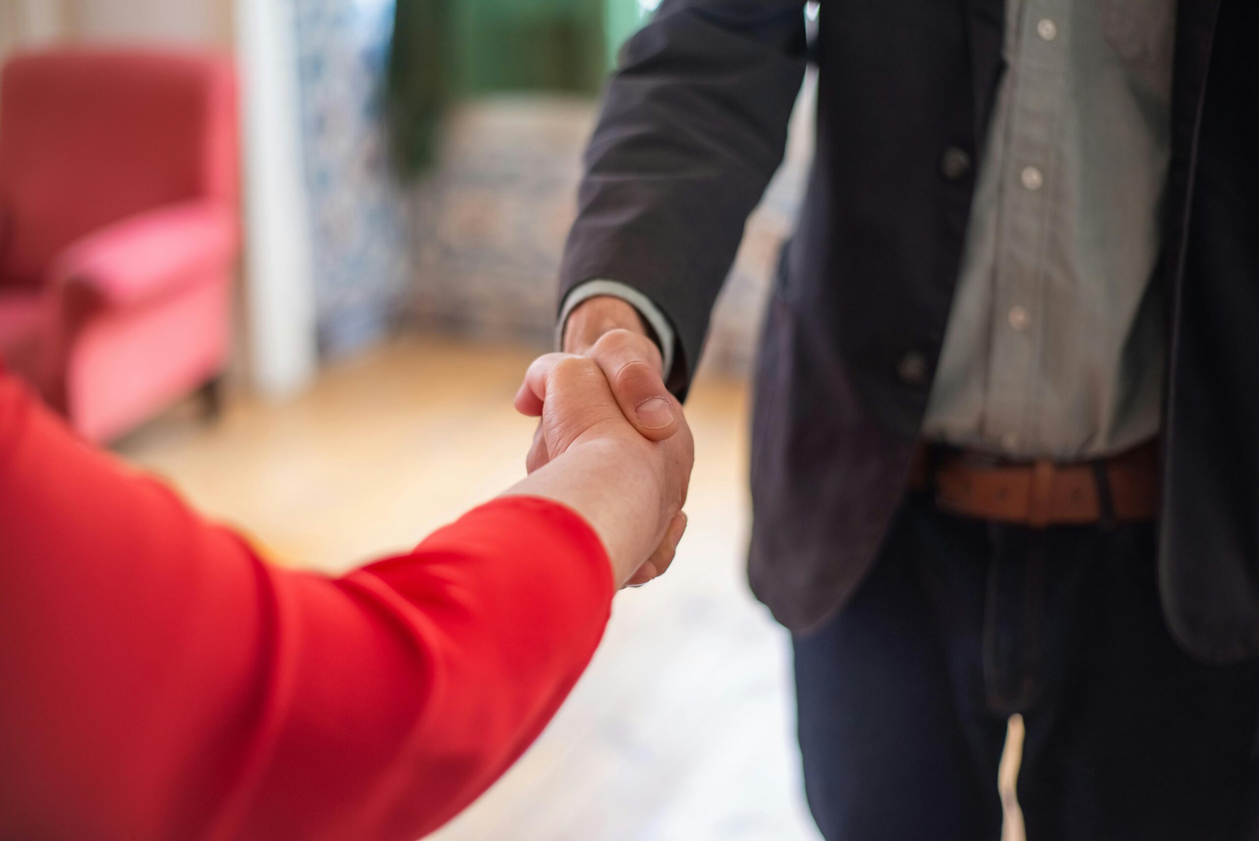 Close-up view of two people shaking hands indoors, symbolizing agreement or partnership.